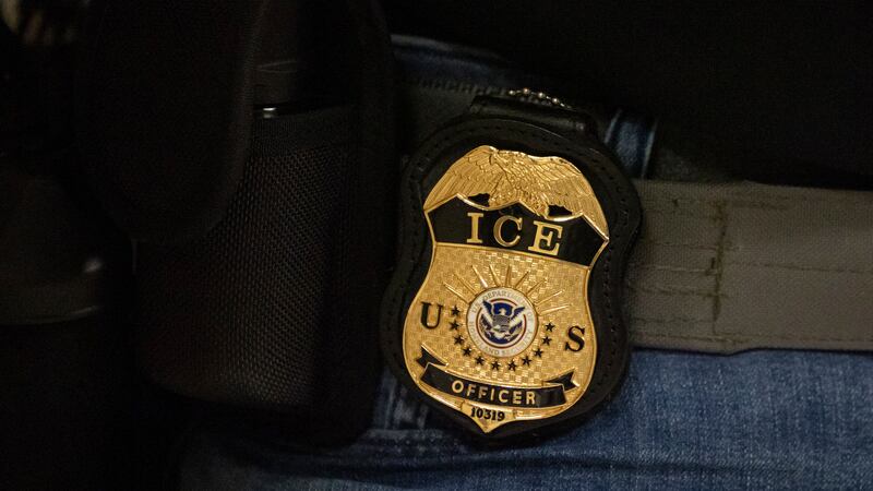A federal agent wears a badge of Immigration and Customs Enforcement while standing outside an...