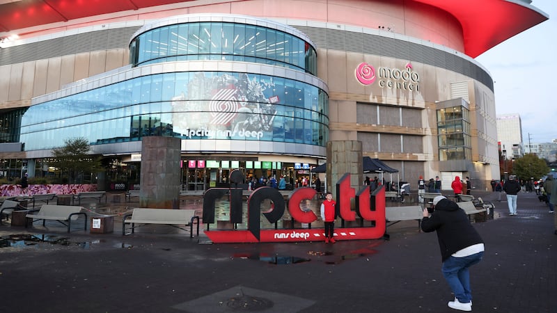 A fan poses for a photo Moda Center before an NBA basketball game between the Portland Trail...